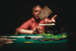 One mature man playing poker late by night, throwing playing cards on table.